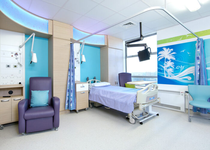 Hospital room furnished in purple and turquoise with co-ordinating wall art depicting swirly patterns.