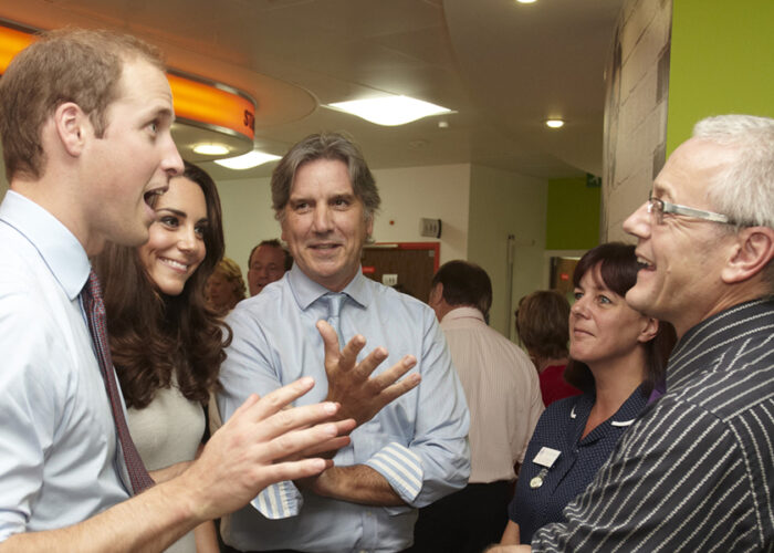 Prince William and Kate with a group of people talking to Colin in a room