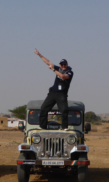 Picture of Colin Horn, Managing Director and founder of Grosvenor Interiors dabbing whilst standing on the bonnet of a jeep.