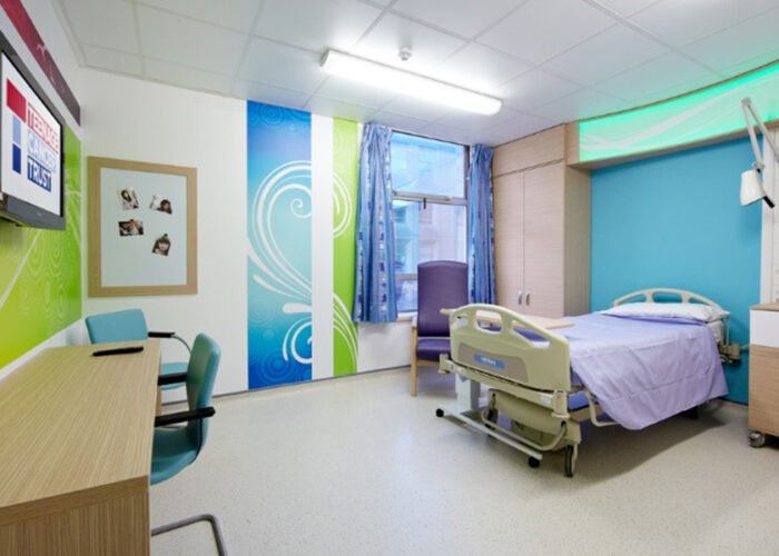 Teenage Cancer Trust hospital room with wall art and co-ordinating furniture including bed, chair and desk.